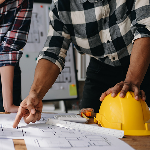 Profesional revisando planos con equipo de construcción